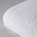 A close up of a white knitted fabric on a white surface.