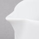An Arcoroc white porcelain creamer with a curved handle.