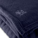 A close up of a navy blue Oxford fleece blanket with a small embroidered logo.