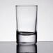 A close-up of a clear Arcoroc shot glass on a table.