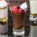 A close up of an Arcoroc shot glass filled with chocolate pudding and raspberries with whipped cream on top.