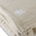 A close up of an Oxford vanilla fleece blanket with white embroidered logo.