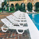 A row of white Grosfillex Bahia chaise lounges.