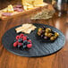 A Tablecraft Frostone faux slate melamine tray with fruit and cheese on it.