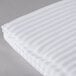 A close up of a white and white striped Oxford Super Blend hotel duvet cover.