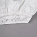 A white Oxford Super Deluxe fitted sheet with ruffles on a gray surface.