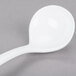 A Tablecraft white cast aluminum long ladle with a handle on a gray surface.