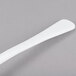 A Tablecraft white cast aluminum long ladle with a white handle on a gray surface.