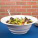 A white Tablecraft cast aluminum salad bowl on a table with salad.