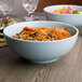 Two bowls of noodles and vegetables in blue melamine bowls.