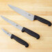 A Victorinox 3 piece chef knife set with black handles on a table.