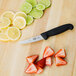 A Victorinox chef knife with a black handle next to sliced lemons and strawberries.