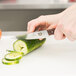 A person cutting a cucumber with a Victorinox steak knife.