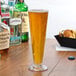 A Thunder Group plastic footed pilsner glass of beer on a table