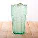 A green Thunder Group polycarbonate tumbler filled with ice water on a wooden table.