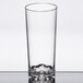 A clear Thunder Group plastic beverage glass with a small amount of milk inside.