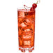 A Thunder Group plastic heavy base beverage glass filled with red liquid with ice and a cherry on top.
