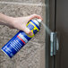 A person using WD-40 spray to lubricate a door.