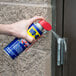 A person using WD-40 spray to lubricate a door handle.