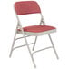 A gray metal folding chair with a red padded seat.