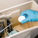 A person in blue gloves using a 2000 Flushes Blue Plus Bleach toilet bowl cleaner.