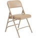 A beige National Public Seating metal folding chair with a French beige vinyl padded seat.