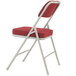 A gray metal folding chair with a new burgundy fabric padded seat.