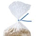 A plastic bag with rice in it closed with a blue paper twist tie.
