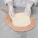 A person in white gloves using an American Metalcraft pizza peel to make pizza dough.