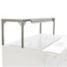 A white table with a stainless steel Delfield single overshelf on top.