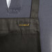 A black Chef Revival bib apron with yellow text on the front pocket.