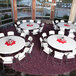 A 72" round white plastic Lifetime folding table with white chairs and a red napkin on it.