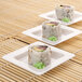 Three Fineline white plastic trays with sushi rolls on them.