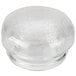 A clear glass container with a round top over a close-up of a white surface.