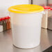 A white Rubbermaid polyethylene food storage container with a yellow lid.