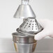 A gloved hand holding a metal cone for a juicer.