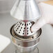 A gloved hand using a Nemco metal cone for a juicer.