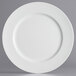 A close-up of a white Charge It by Jay plastic charger plate with a round edge.