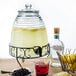 A glass jar with a drink and a black spigot filled with lemonade and berries with lemons on the table.
