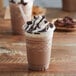 A close-up of a chocolate mocha drink with whipped cream and chocolate chips, made with Big Train Mocha Blended Ice Coffee Mix.