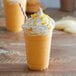A glass of Big Train Orange Cream Kidz Kreamz Frappe with whipped cream and a straw.