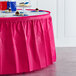 A table with a hot magenta pink Creative Converting plastic table skirt on it.