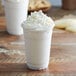 A white drink made with Big Train White Hot Chocolate Mix topped with whipped cream in a plastic cup.