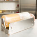A Bulman stainless steel countertop film dispenser with a roll of plastic wrap on it.
