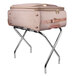 A pink suitcase on a Lancaster Table & Seating Chrome folding luggage rack.