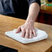 A person wiping a white Choice terry bar towel on a counter.