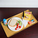 A Cambro Tuscan Gold dietary tray holding a sandwich, chips, and a drink.