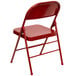 A red metal folding chair with a backrest.