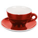 A close-up of a CAC red tea cup and saucer with white trim.