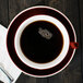 A CAC Venice red cup of coffee on a saucer with a spoon